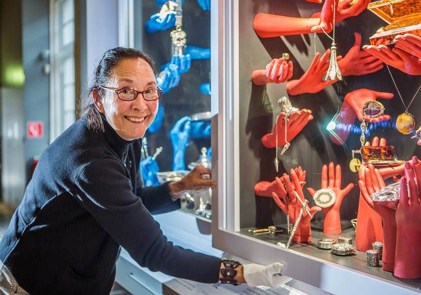 Vrouw met bril met handschoenen aan opent vitrine in Zilvermuseum
