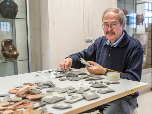 Man zit aan tafel met scherven van aardewerk