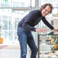Man leunt op glazen vitrine in museum