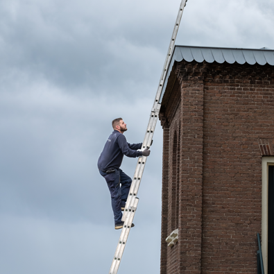 Monumentenwachter beklimt een ladder en inspecteert een pand