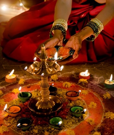 Vrouw in indiaase kledij steekt kaarsen aan