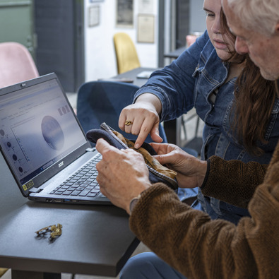 Foto van twee personen achter de laptop wijzend naar een object