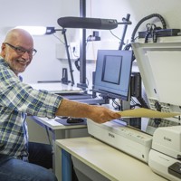 Digitalisering: man achter laptop en naast scanner scant een formulier.