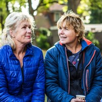 Twee vrouwen zitten in tuin en praten met elkaar