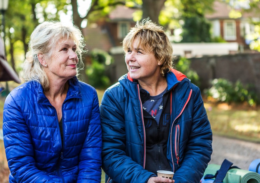 Twee vrouwen zitten in tuin en praten met elkaar