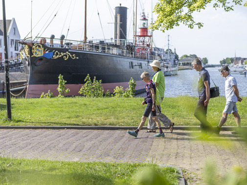 wandelende vrijwilligers met op de achtergrond het ramtorenschip