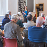 Vrouw vertelt verhaal voor groep mensen die op stoelen zitten