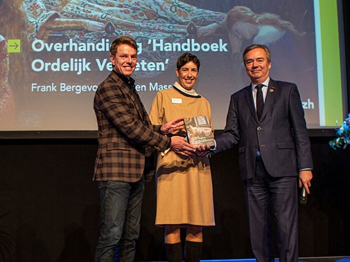 Evelien Masselink en Frank Bergevoet reiken het eerste exemplaar van Handboek Ordelijk Vergeten uit aan gedeputeerde Meindert Stolk. Foto: Floris Scheplitz