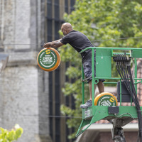 Man op hoogwerker hangt buiten een kaas op met de tekst: 