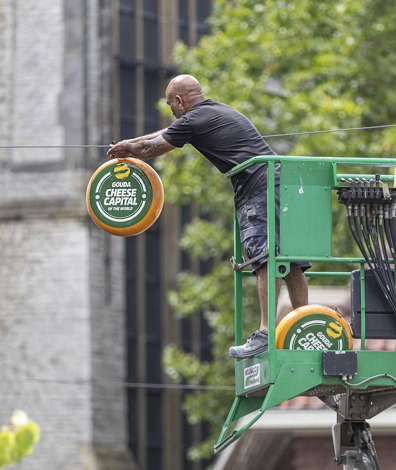 Man op hoogwerker hangt buiten een kaas op met de tekst: 
