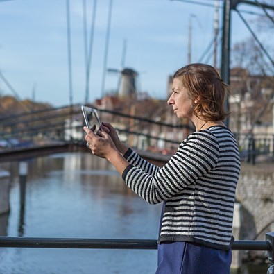 Vrouw met tablet maakt foto met brug op achtergrond