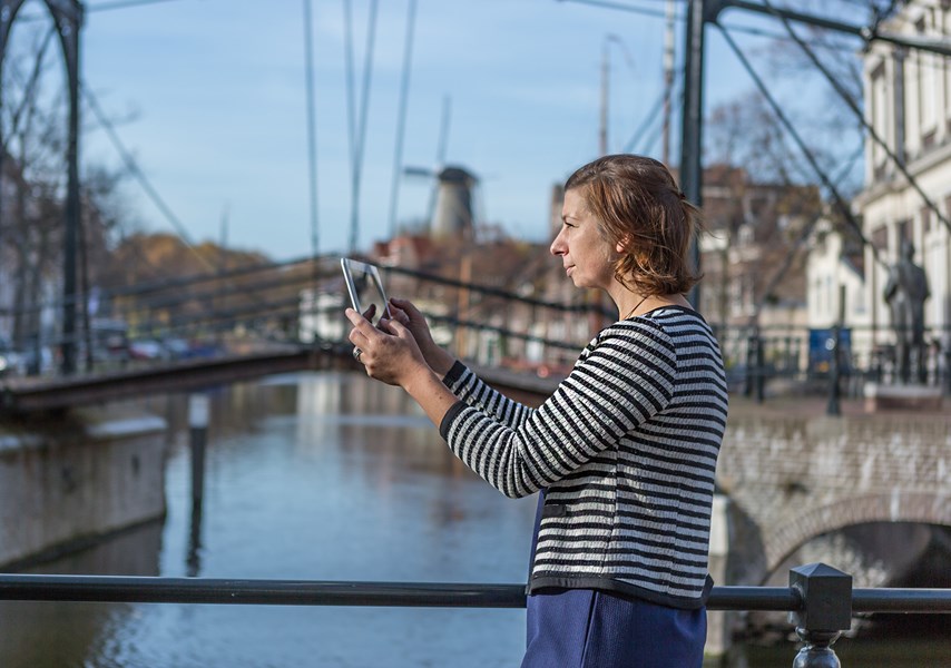 Vrouw met tablet maakt foto met brug op achtergrond