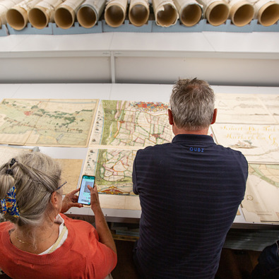 In het Nationaal Archief: deelnemers bezoeken het Nationaal Archief en bekijken kaarten.