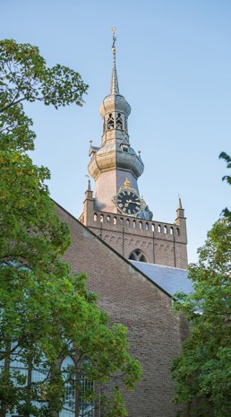 Kerktoren met spits dak en grote klok