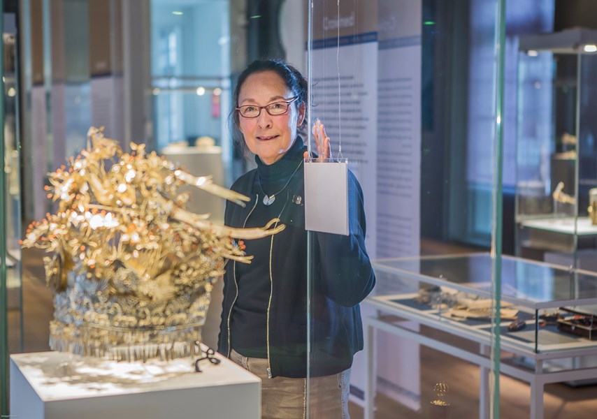 Vrouw met bril bekijkt collectie Zilvermuseum in glazen vitrine