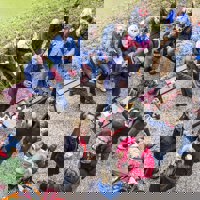 Grote groep mensen zit in tuin en drinkt koffie
