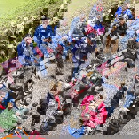 Grote groep mensen zit in tuin en drinkt koffie