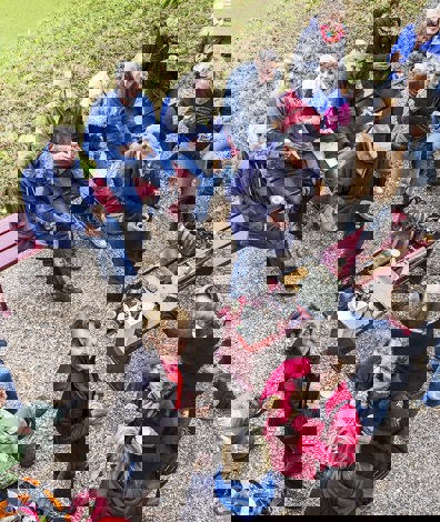 Grote groep mensen zit in tuin en drinkt koffie