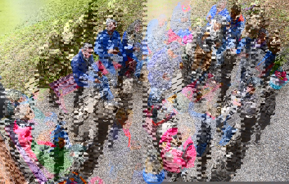 Grote groep mensen zit in tuin en drinkt koffie