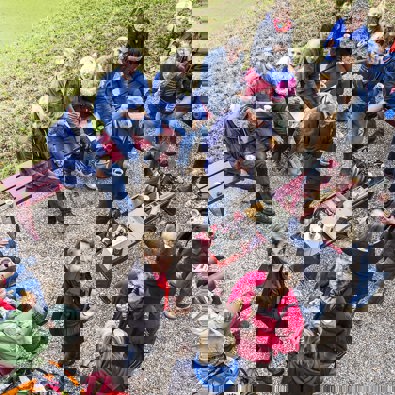 Grote groep mensen zit in tuin en drinkt koffie