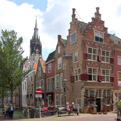 Mensen lopen op Oude Delft met op achtergrond de Nieuwe Kerk