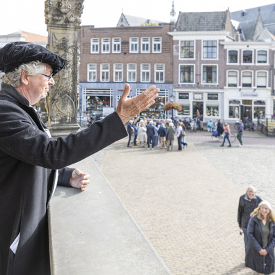 Rondleider vertelt een verhaal beeldend met handen aan groep mensen