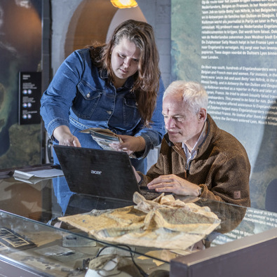 Foto van twee personen achter een laptop in een tentoonstellingsruimte