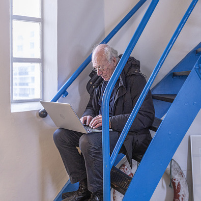 Man zit op trap met een laptop op schoot te zoeken naar informatie
