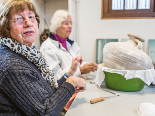 Twee vrouwen zitten aan tafel met gereedschap en amfoor
