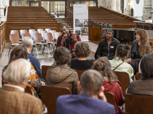 Drie sprekers zitten in het schip van de Sint-Janskerk in Gouda voor een kleine groep bezoekers met wie ze in gesprek zijn over Hiphop-erfgoed.